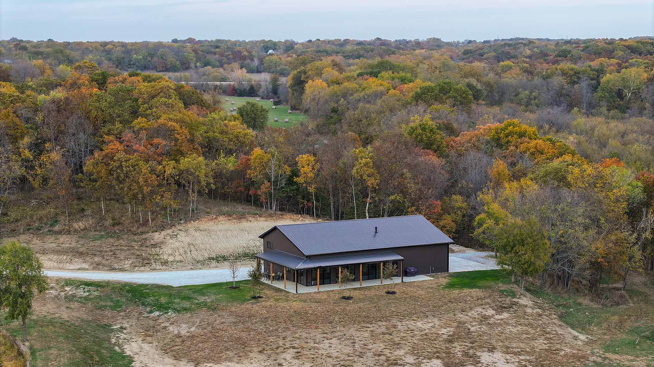 Red Bird Ranch event building nestled in autumn woodland — aerial view