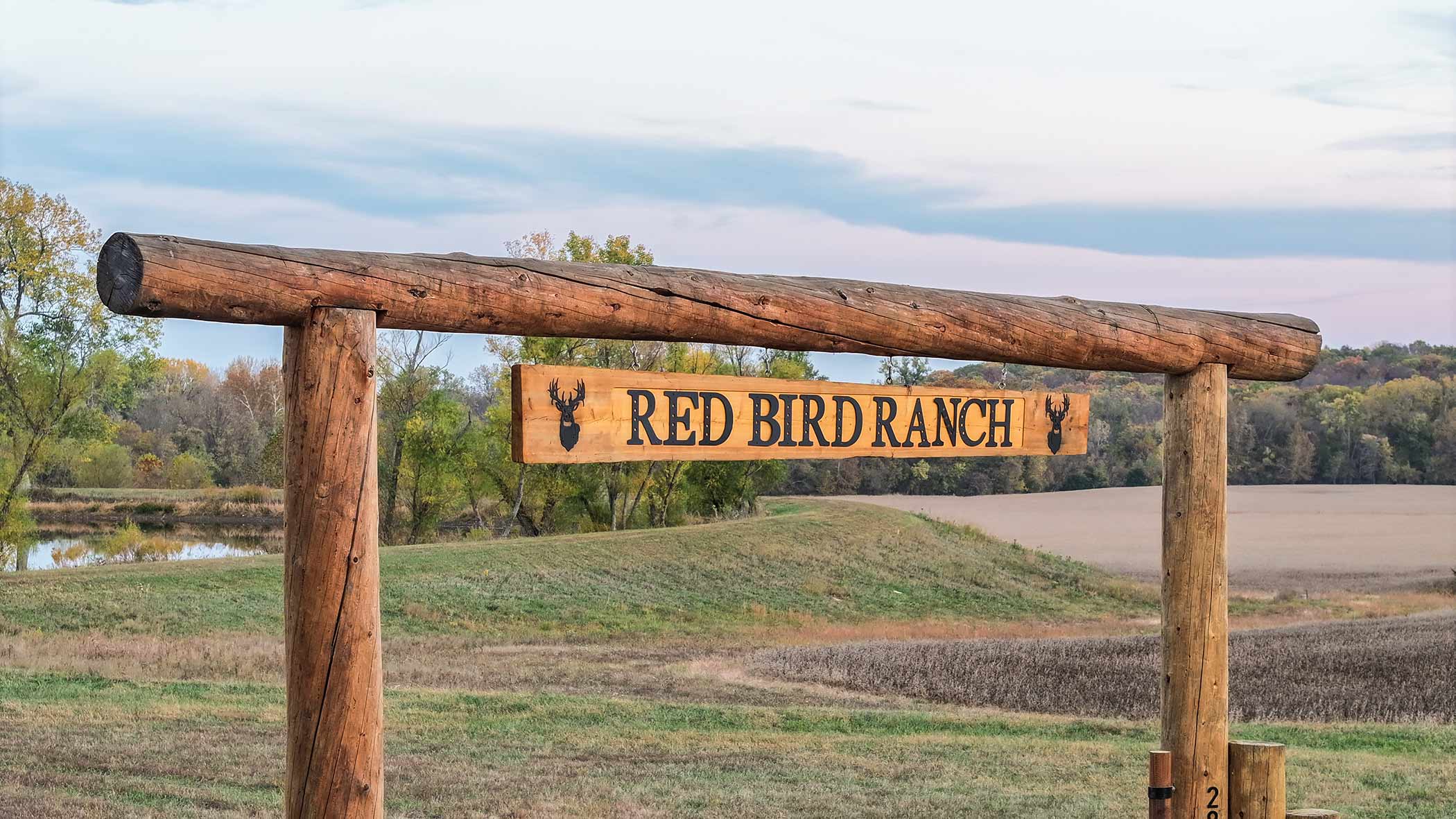 Red Bird Ranch entrance sign — carved wood plank with deer head silhouettes
