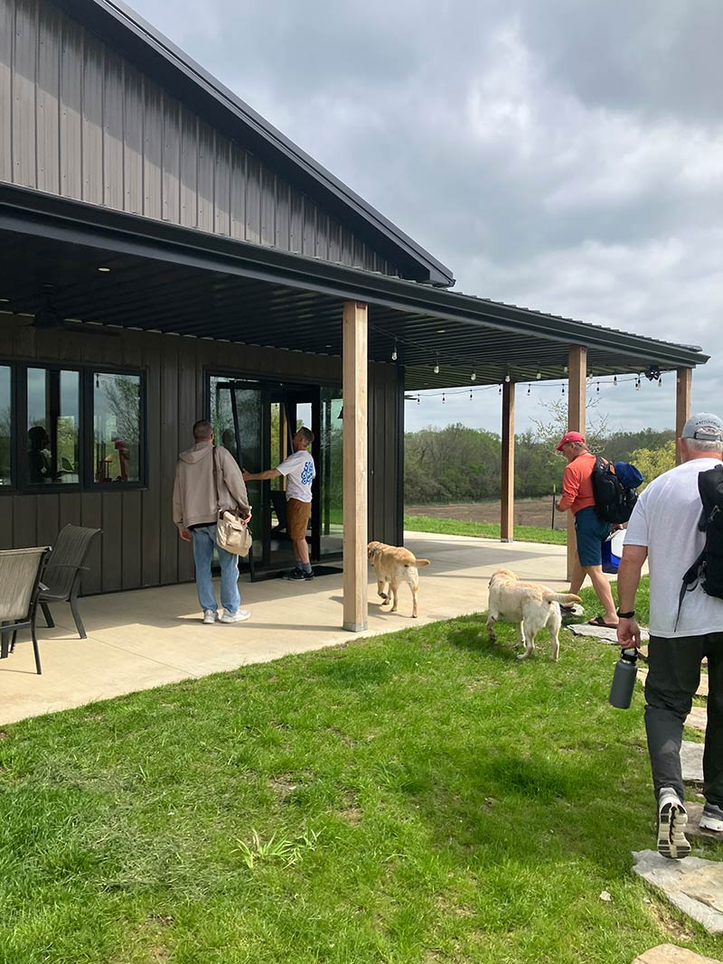 Guests entering through the large glass porch doors at Red Bird Ranch — string lights overhead