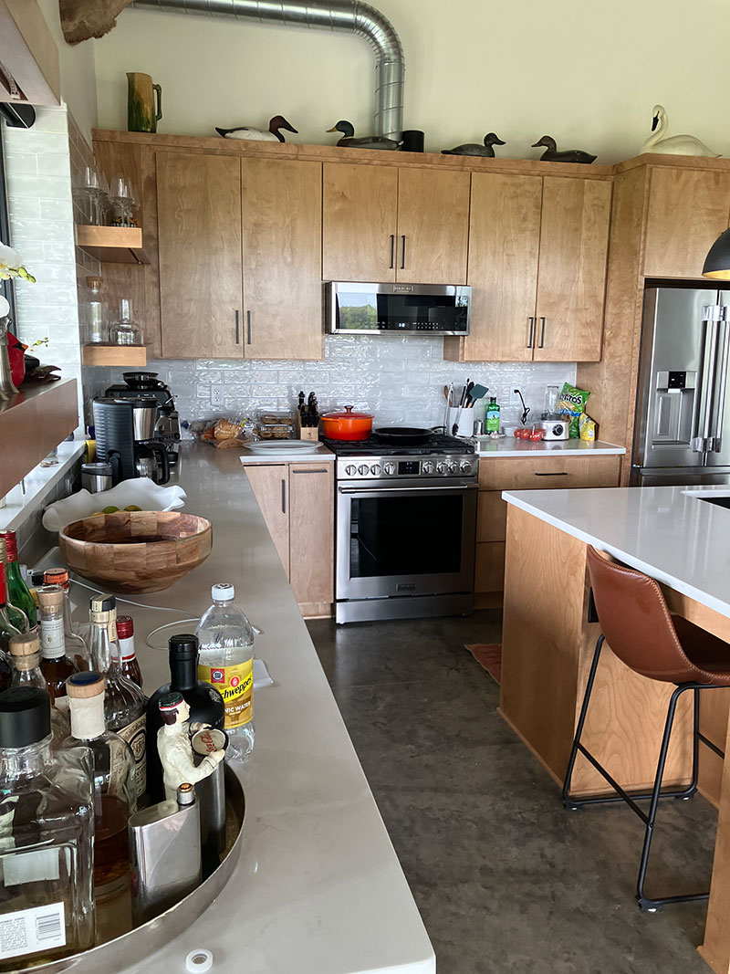 Red Bird Ranch kitchen — wood cabinets, concrete countertops, commercial gas range, fully stocked bar and duck decoys