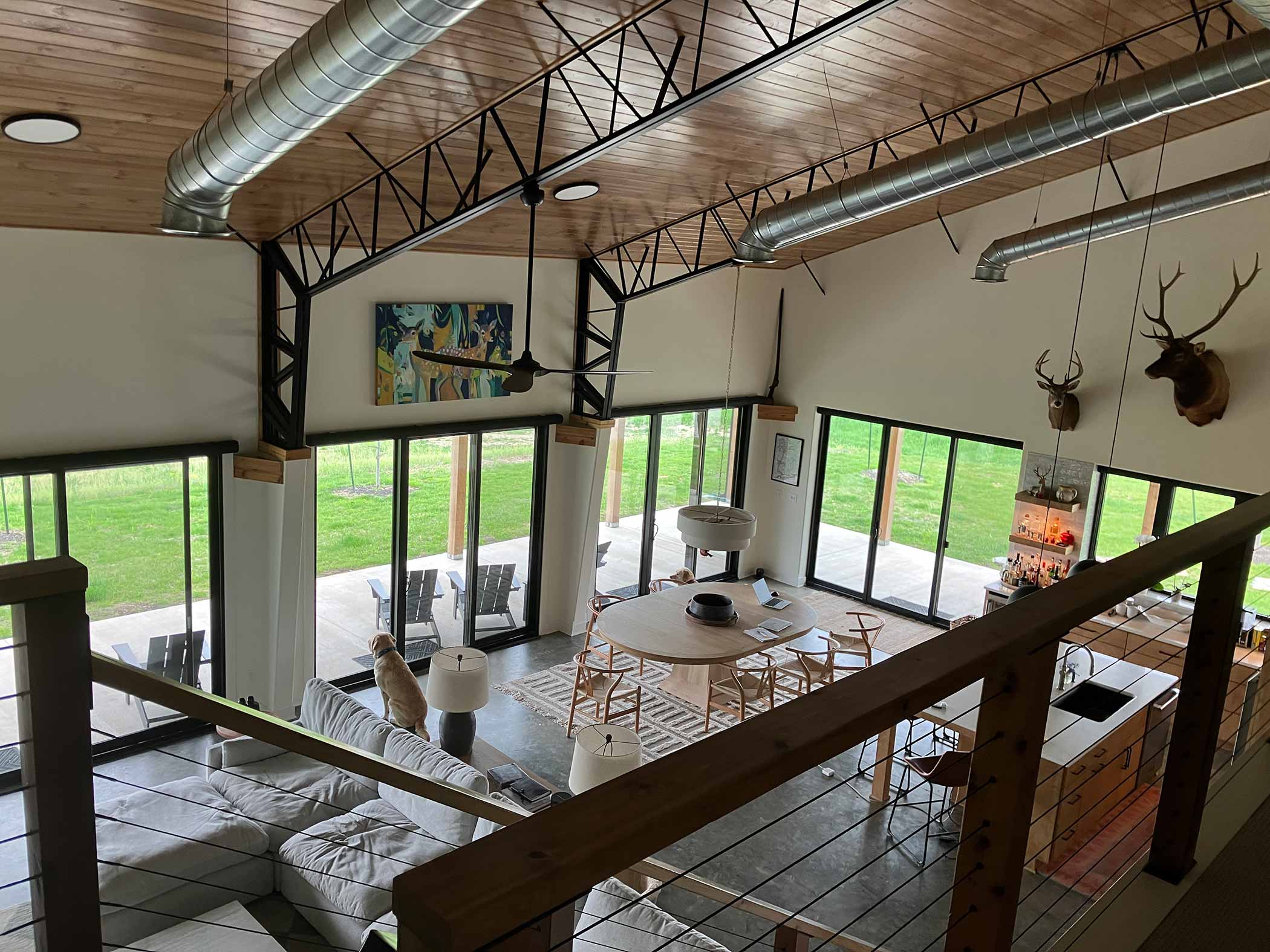 Red Bird Ranch great room interior from mezzanine — vaulted ceilings, stone fireplace, glass walls