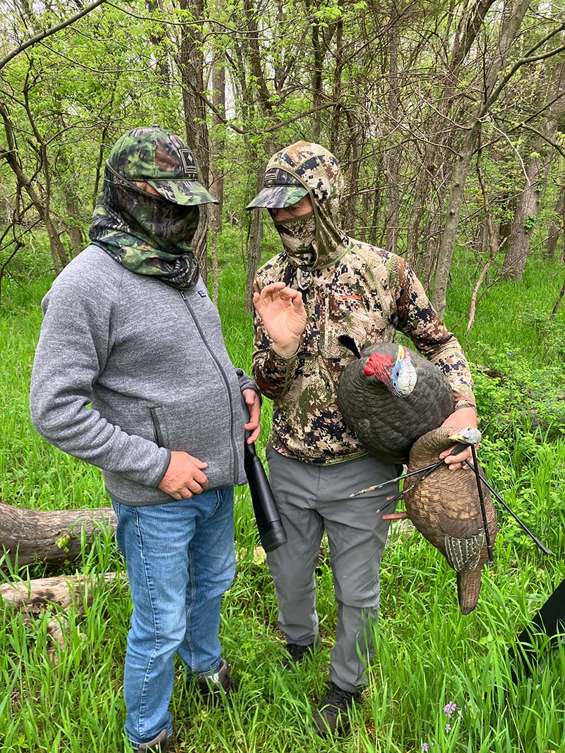 Two hunters in camo with a harvested wild turkey — bonding in the spring woodland at Red Bird Ranch